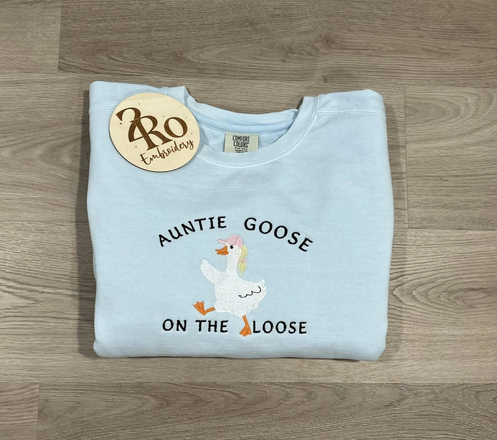 Light-blue Auntie Goose on the Loose sweatshirt with an embroidered white goose wearing a pink cap