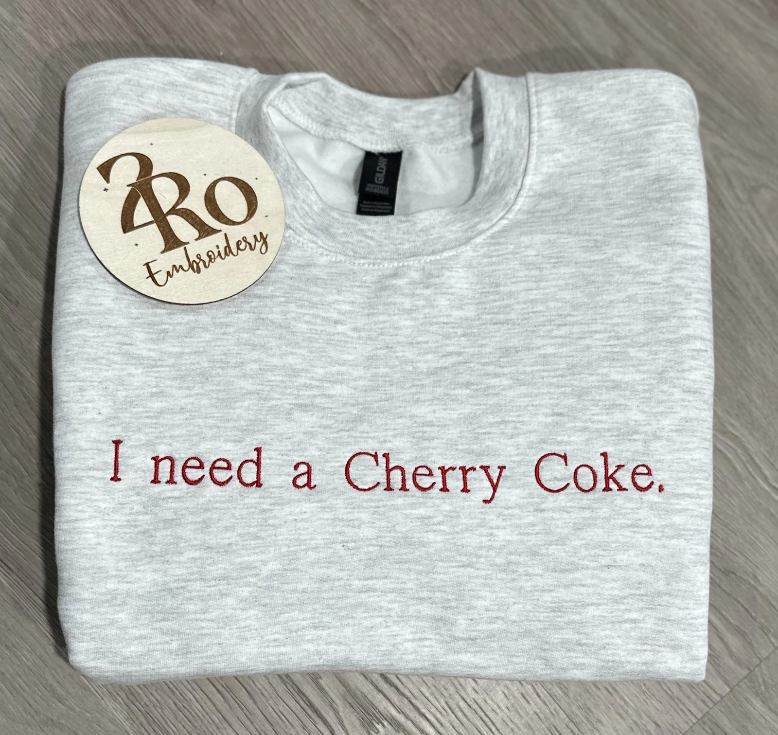 Ash sweatshirt embroidered in red with I need a Cherry Coke.