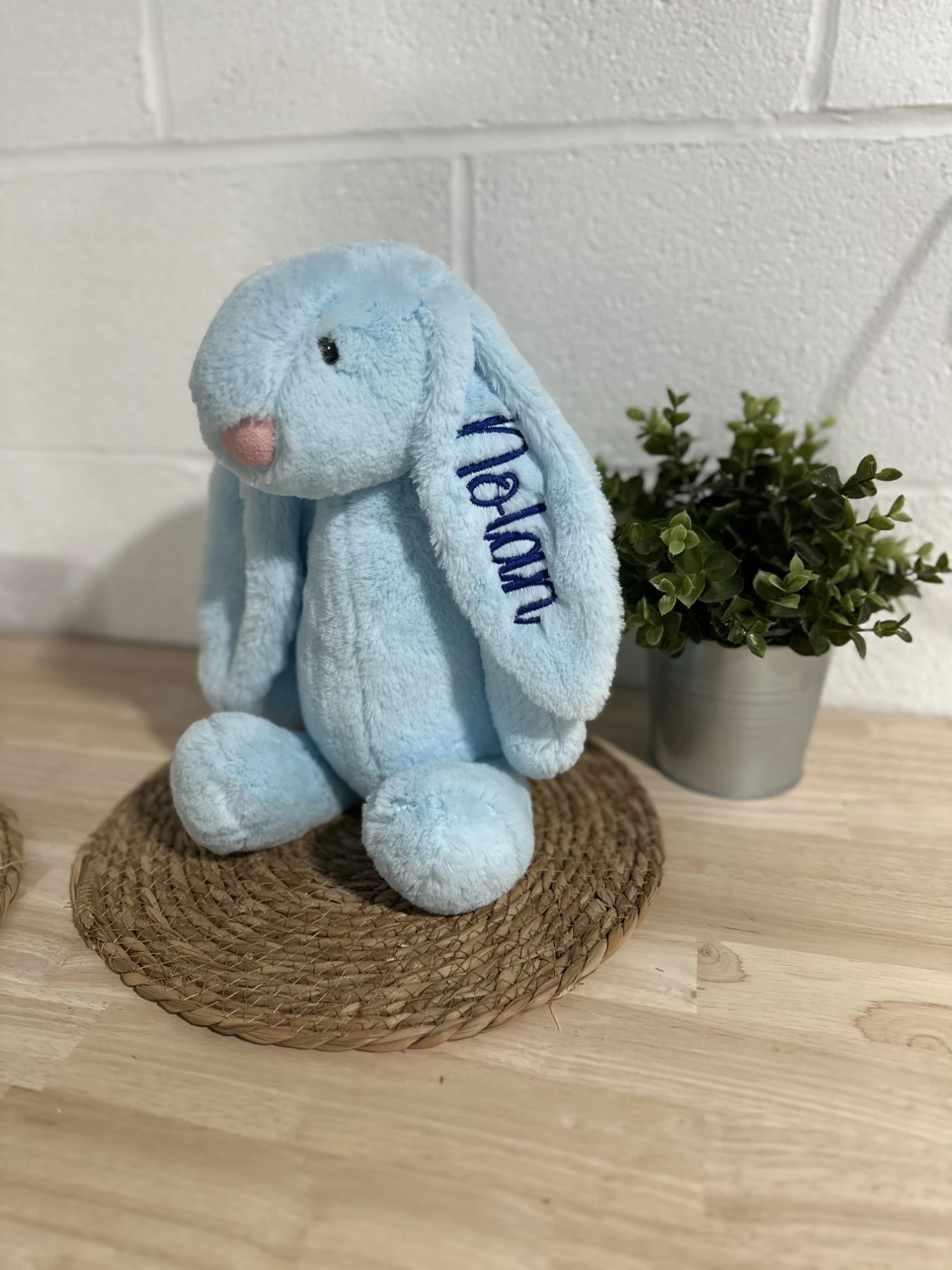 Light-blue plush bunny with a name embroidered in navy down one ear
