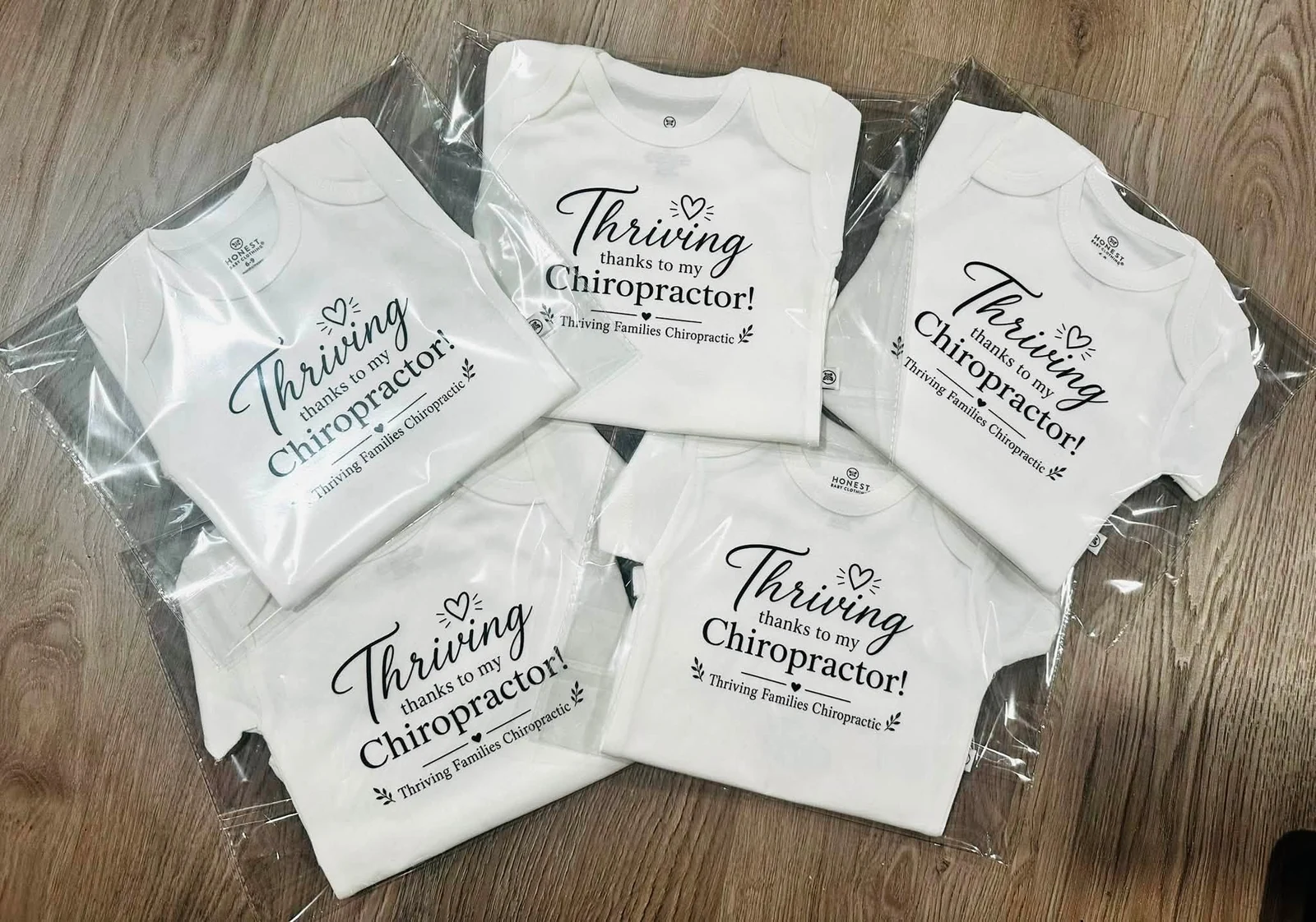 Five white shirts with a black Thriving Families Chiropractic design